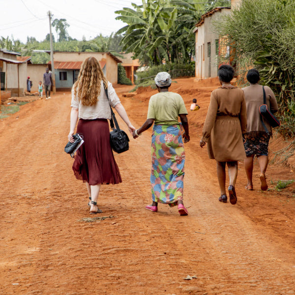 Misiyo's founder and a woman who has received health insurance from us walking on a dirt road in a rural area in Rwanda