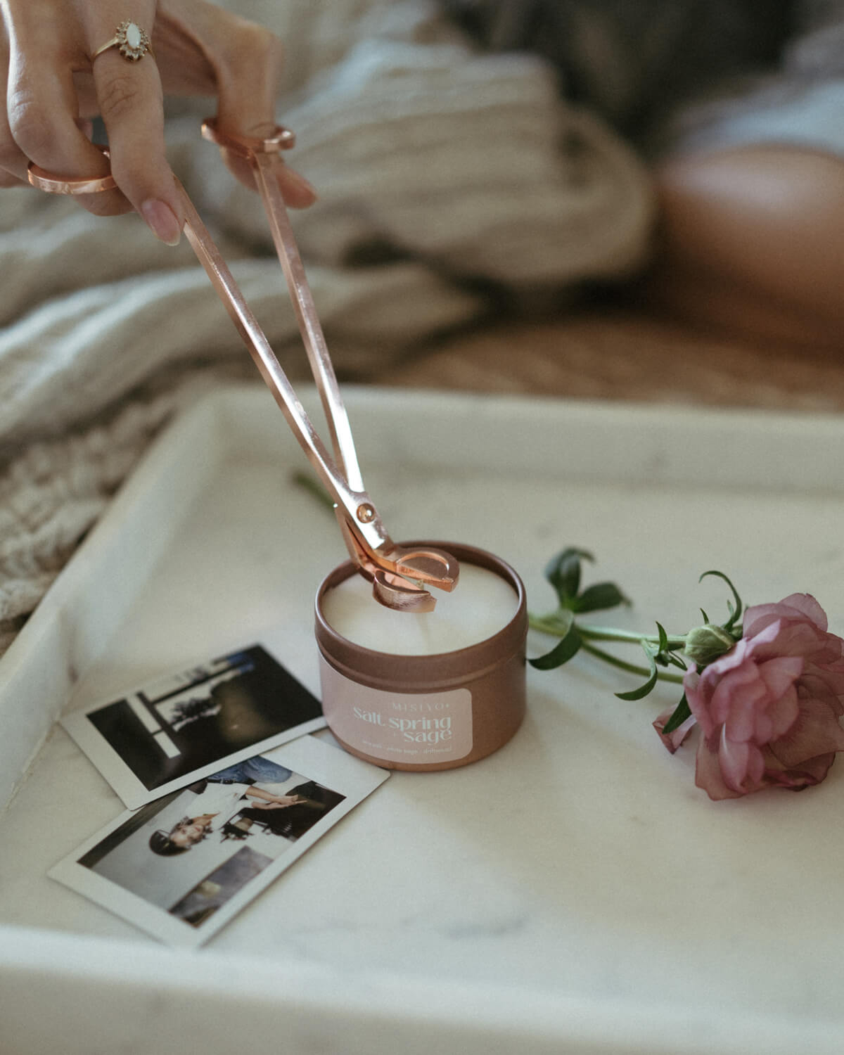 a rose gold wick trimmer being used on a Misiyo rose gold candle tin