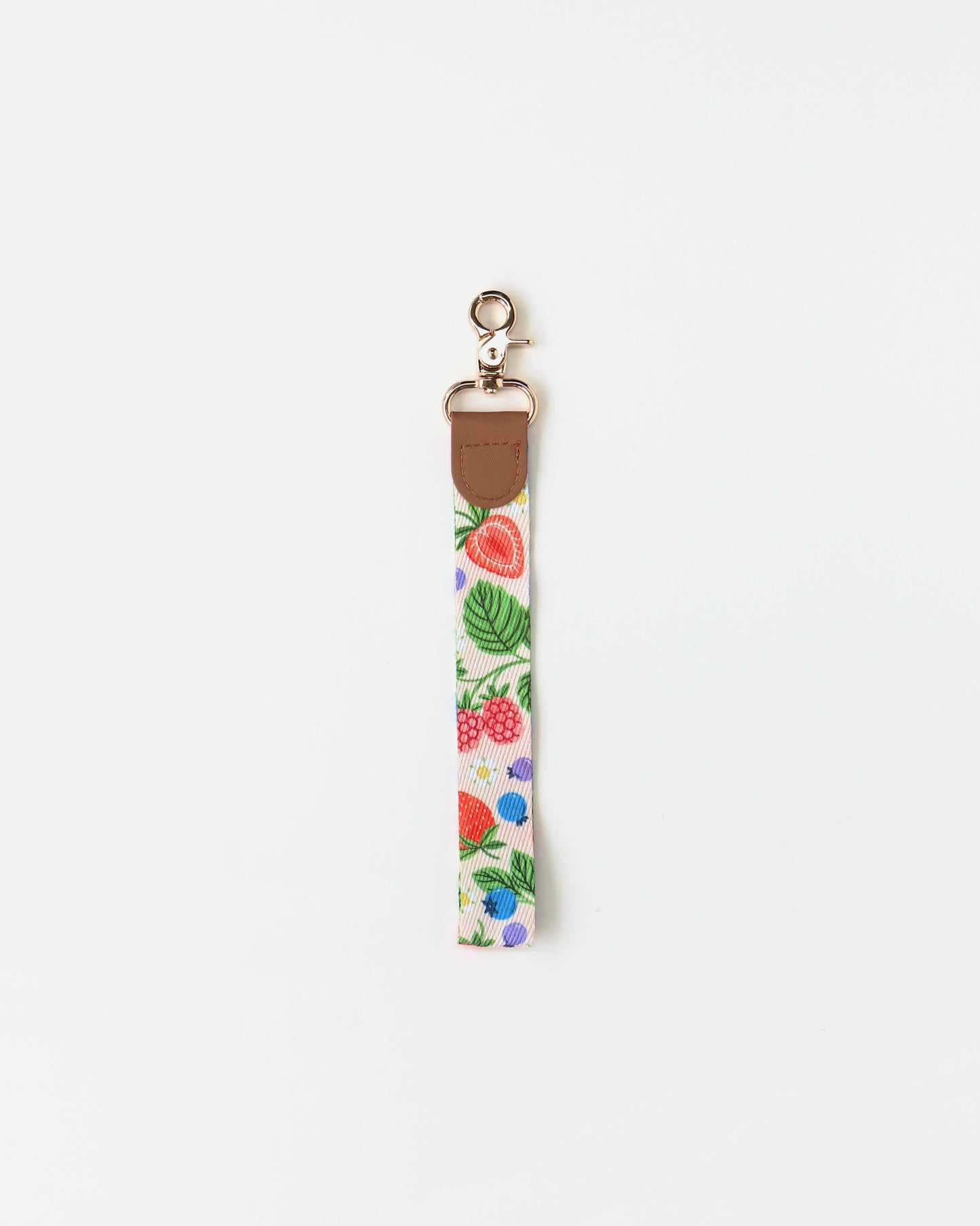 Berries Wristlet Lanyard by Linden Paper Co., a cream polyester strap printed with strawberries, raspberries, blueberries, and green leaves, with a brown PU leather tab and silver lobster clasp — a colourful key wristlet for everyday carry.