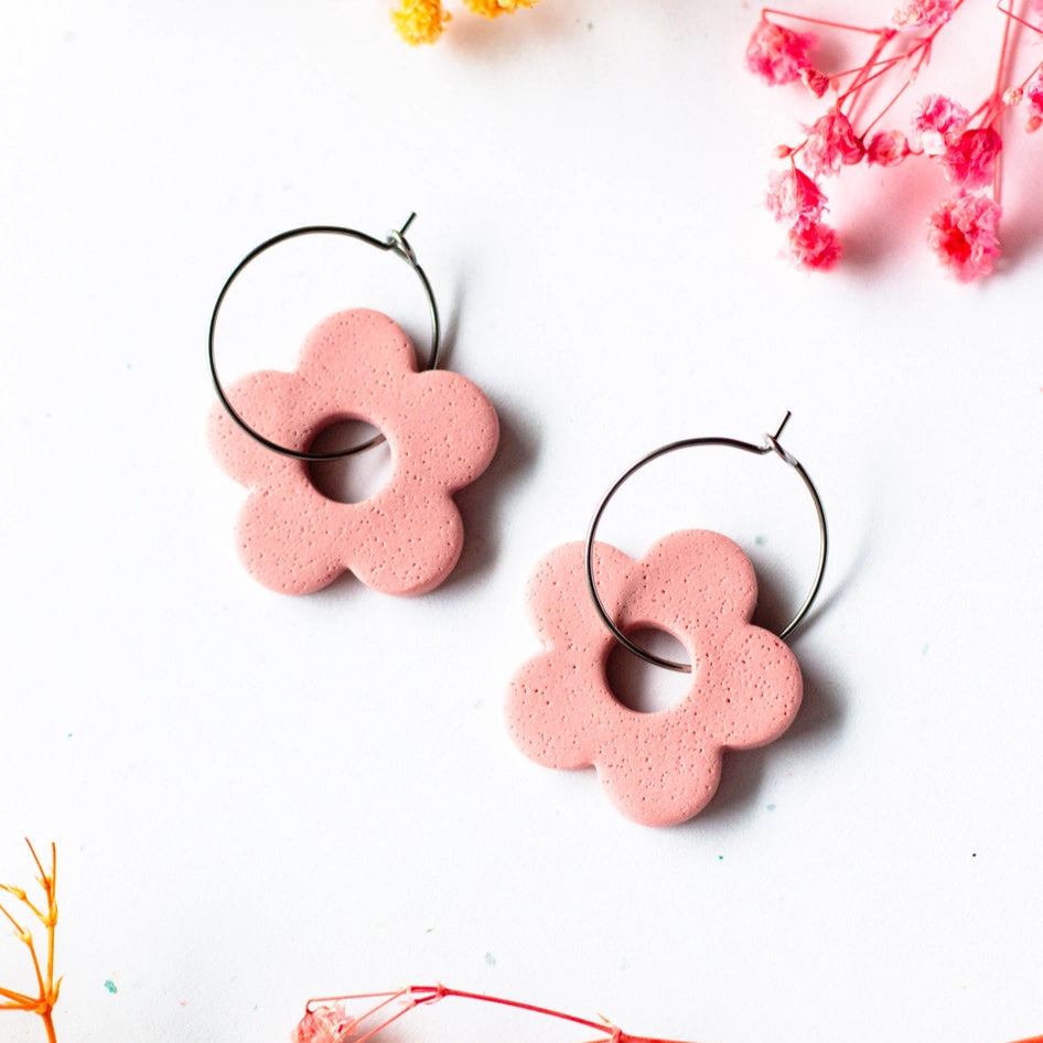 Pink flower-shaped earrings on a white background with dried flowers.