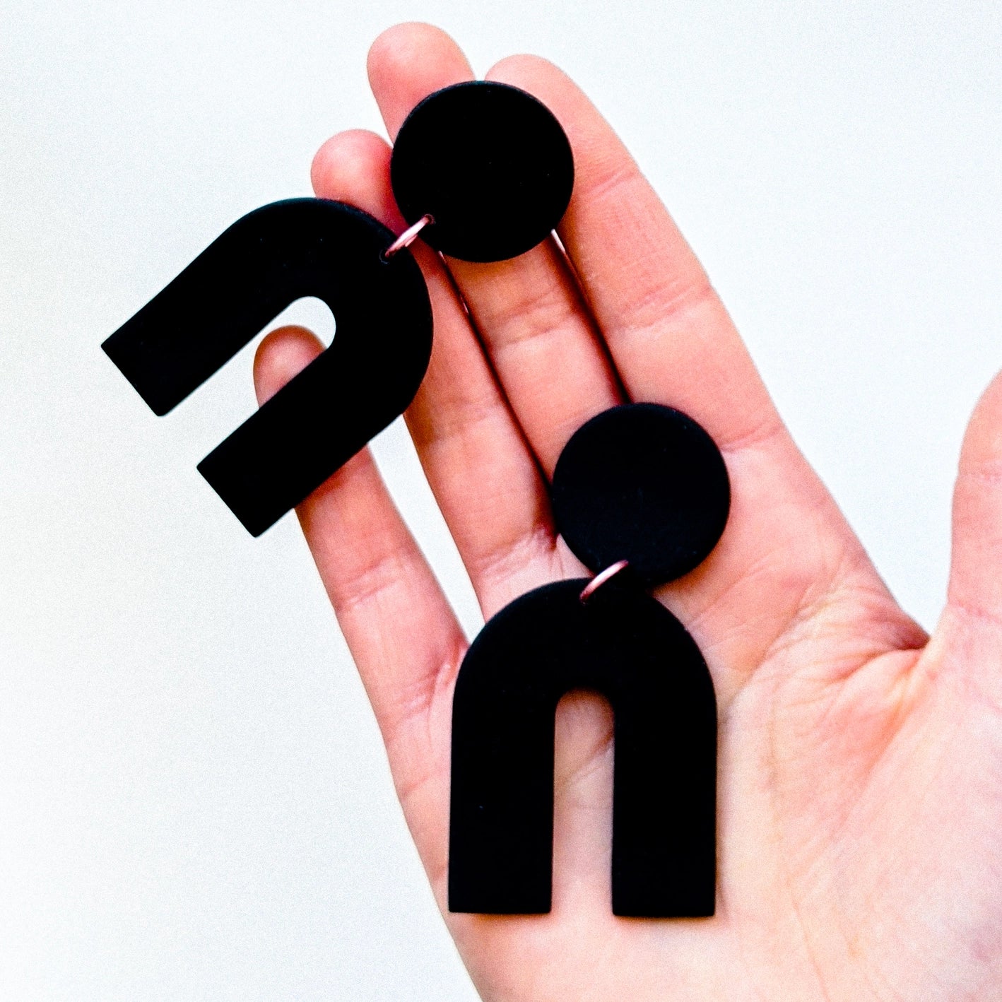black arches ploymer clay earrings held in a hand