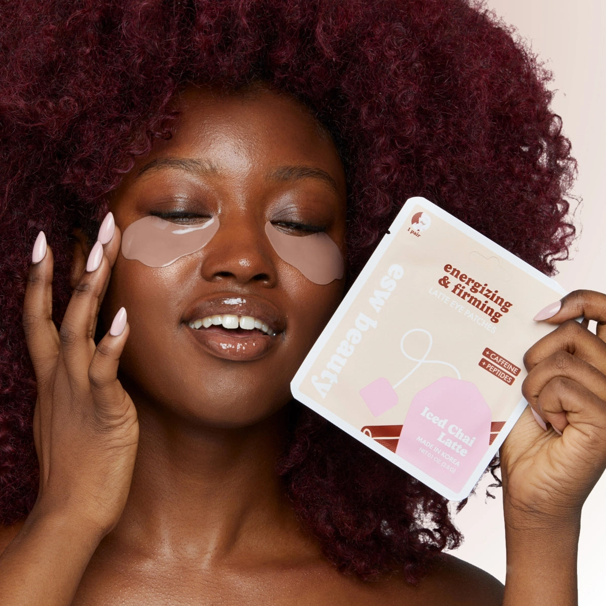 Woman with under-eye patches holding the eye patches packaging. Energizing and firming K-beauty eye patches from ESW beauty.