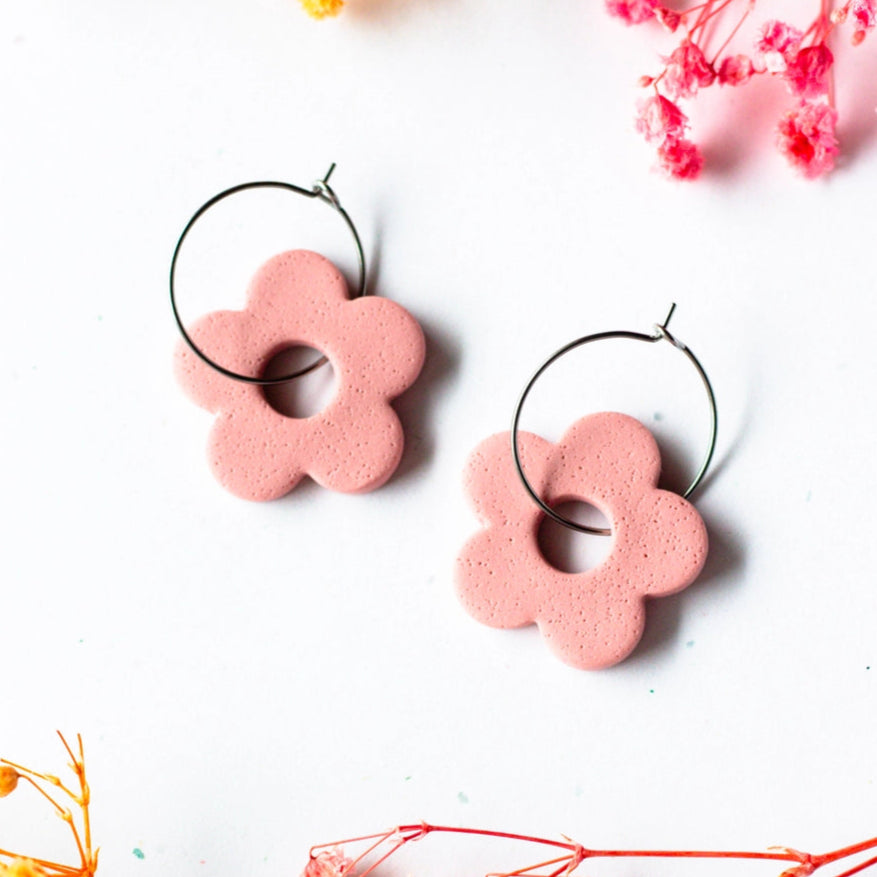 Pink flower-shaped earrings on a white background with dried flowers.
