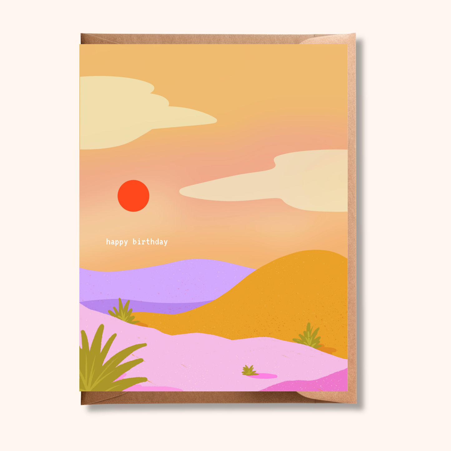 Brush & Bird's Desert Birthday Card featuring a warm illustrated landscape of pink, lavender, and amber rolling hills under an orange sun and golden sky, tucked into a kraft envelope — a colourful birthday card for the desert dreamer or sun lover.
