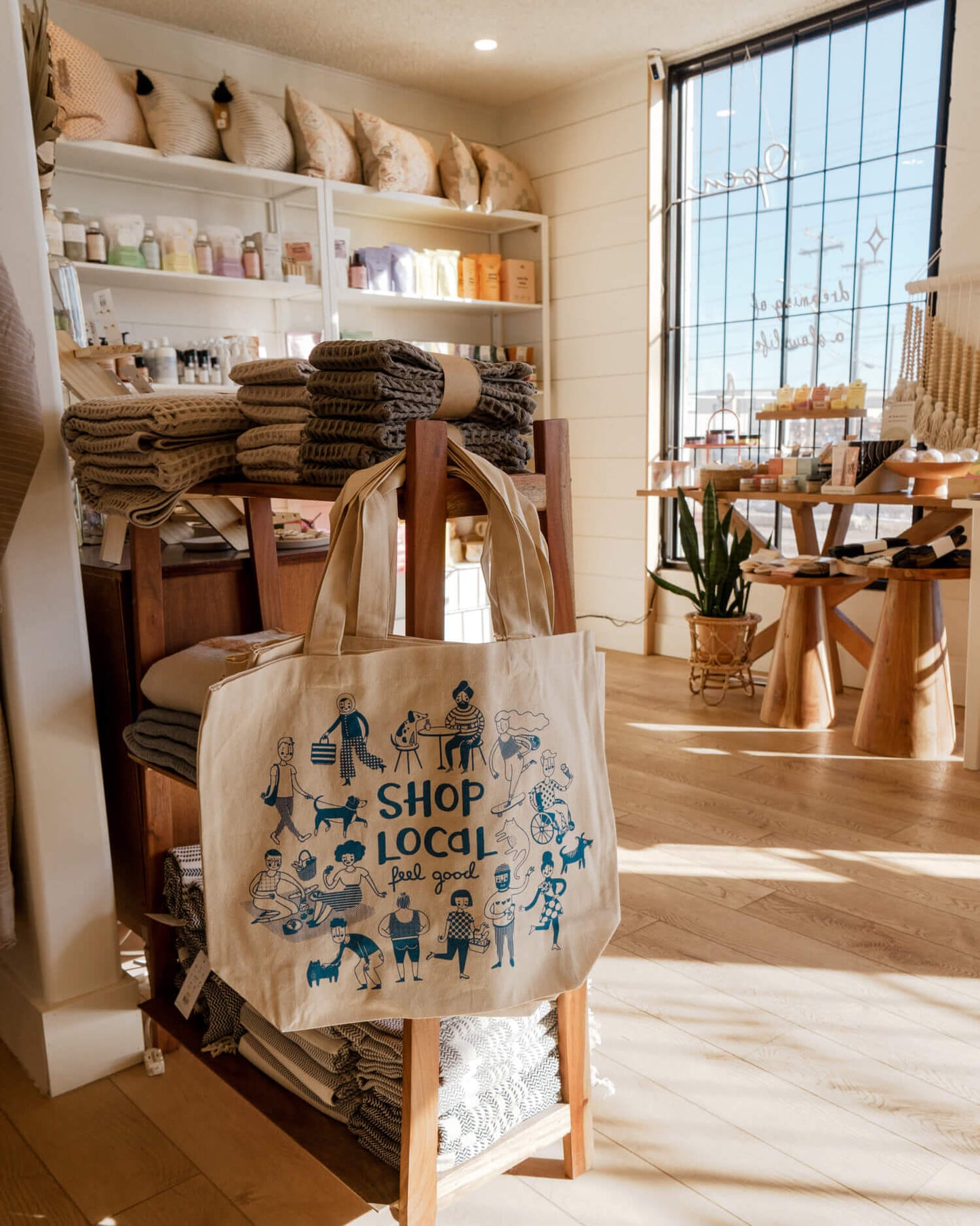 Beige tote bag with 'Shop Local' design on a wooden stand in the Misiyo Slow Living boutique shop