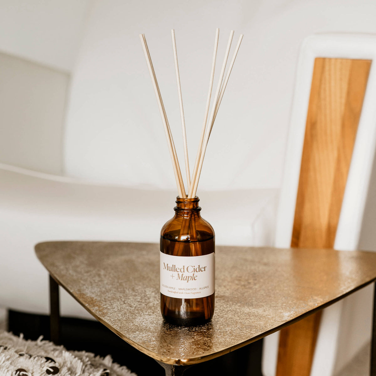 Misiyo Mulled Cider + Maple reed diffuser amber glass jar with reeds shown in a cozy living room setting, warm fall home fragrance, made in Canada