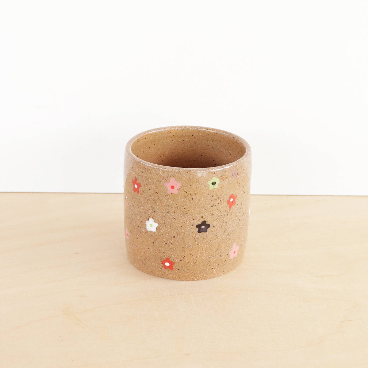 Ceramic planter with colorful dot patterns on a beige surface