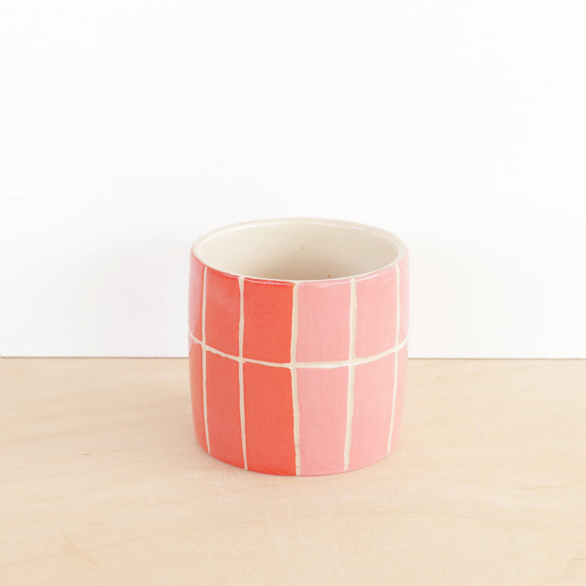 Ceramic planter with pink and white checkered pattern on a beige surface