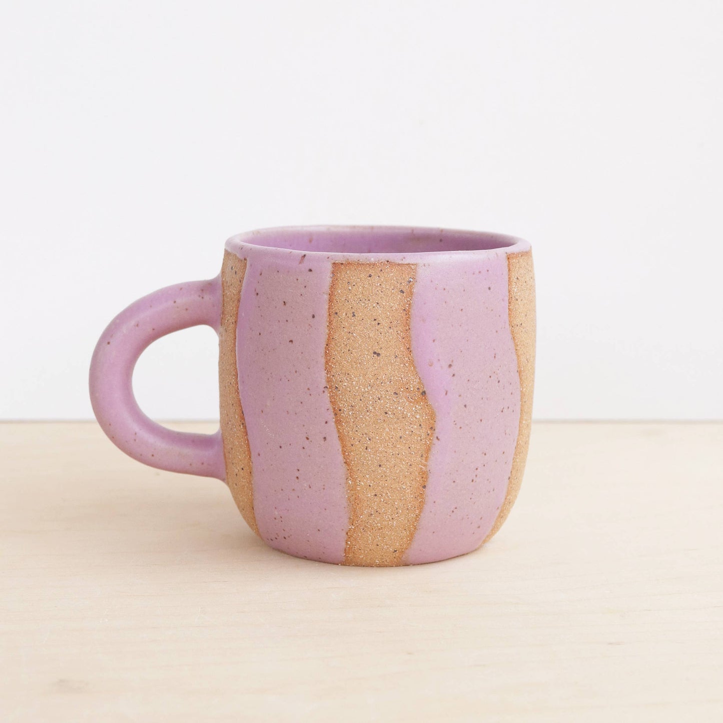 Lilac and beige ceramic mug on a light background