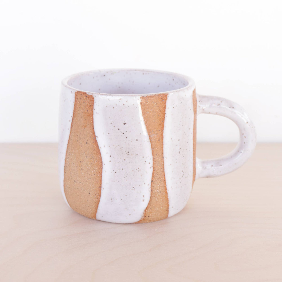 Ceramic mug with white and brown design on a beige background