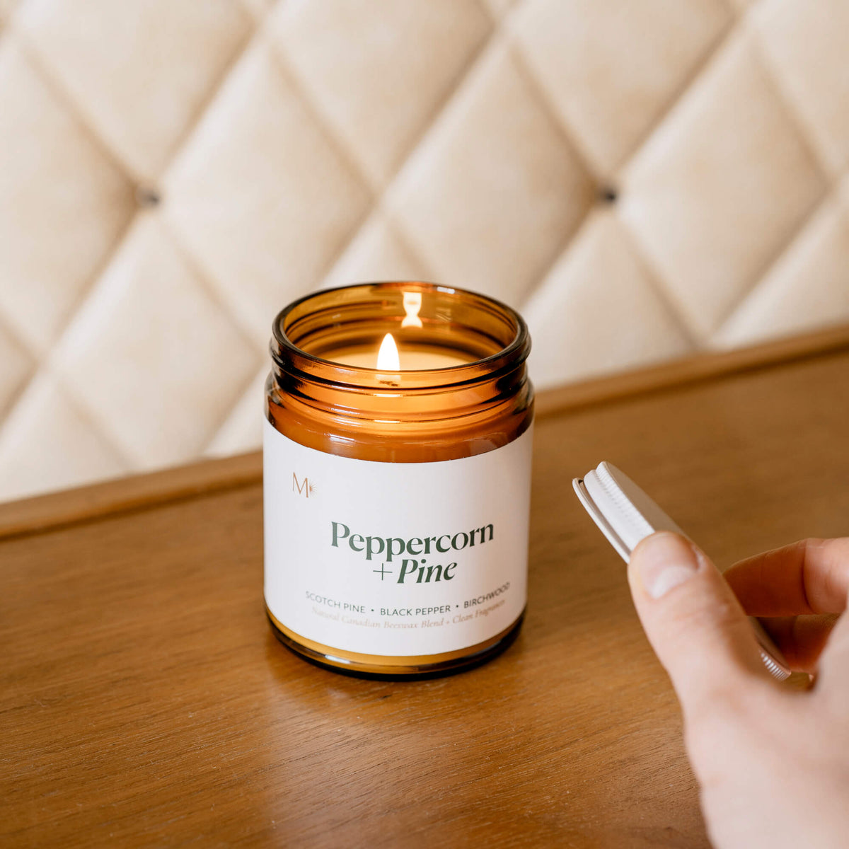Misiyo Peppercorn + Pine holiday candle burning on a wooden surface — woodsy, grounding home fragrance, clean-burning beeswax candle, handmade in Edmonton