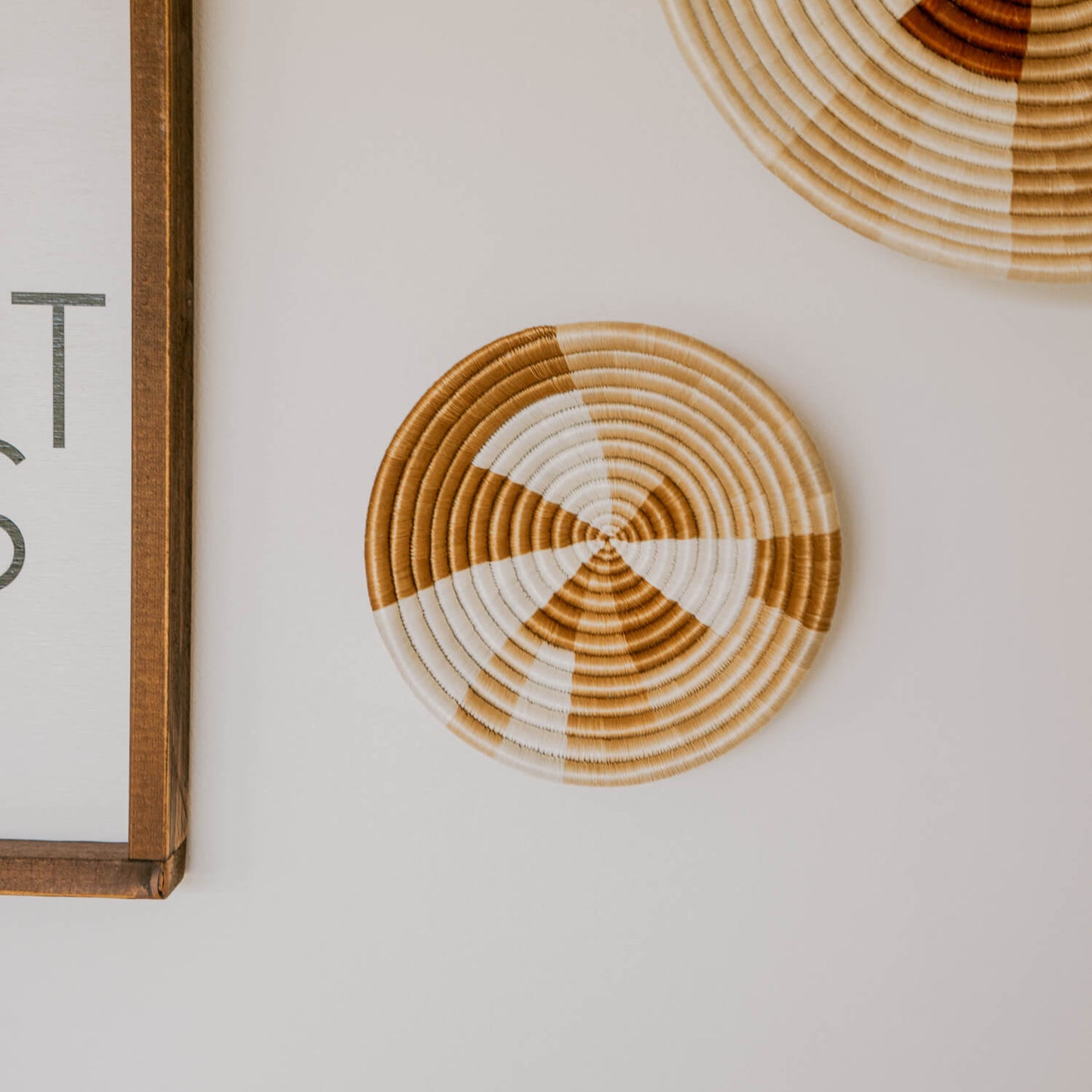 Round woven coasters on a light surface with a framed text piece in the corner.